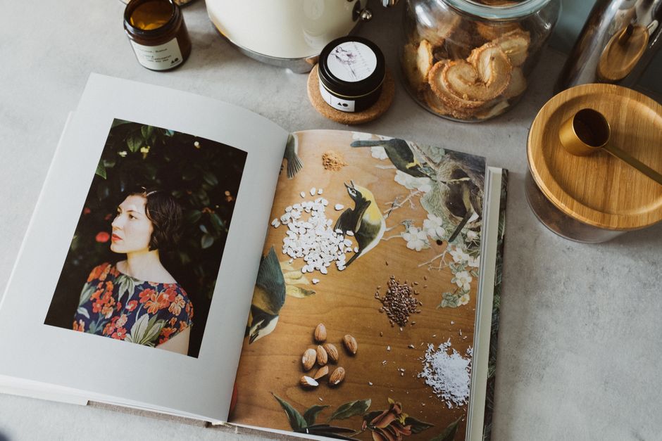 From above of opened recipe book in kitchen among jars with assorted spices
